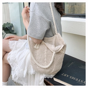 Close-up of off-white crochet shoulder bag featuring fringe detail and knit texture