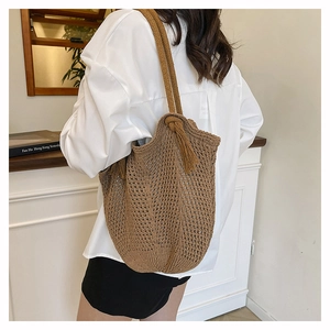 Detail view of large brown knitted tote bag with tassels and mesh texture for summer