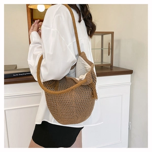 Détail du sac cabas en paille tressée avec texture ajourée et pompon décoratif élégant