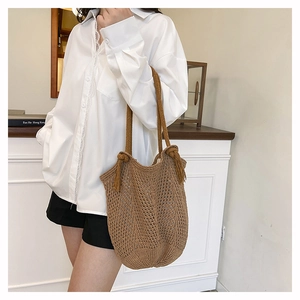 Brown woven tote bag detail showing hollow mesh craft and tassel knots on the strap