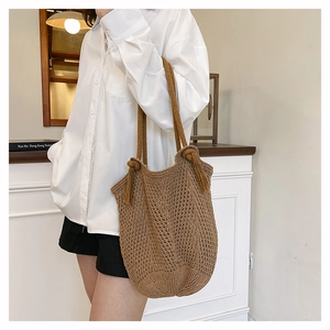 Detailed close-up of brown knitted tote bag featuring hollow mesh texture and tassels