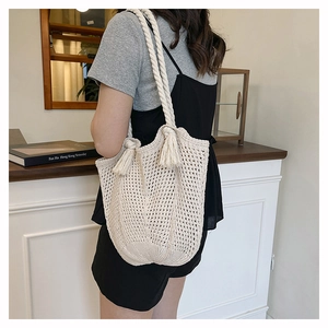 Detail of a minimalist cream crochet tote bag with fringe tassels on the shoulder strap