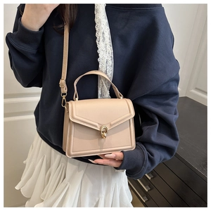 Close-up of beige crossbody bag featuring a golden circular ring metal clasp and leather texture