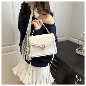 Detail of cream crossbody bag with gold ring buckle worn by model on a clean background