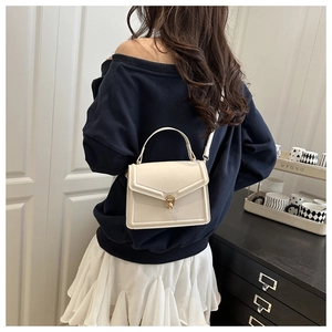 Détail d'un sac à main blanc structuré porté par un mannequin dans un cadre moderne et élégant