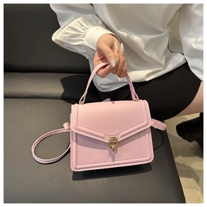 Detail view of pink crossbody bag with gold twist lock and structured top handle
