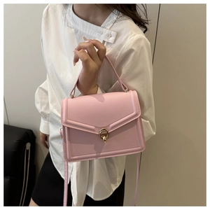 Détail d'un sac à main en cuir rose avec boucle métallique dorée et poignée supérieure