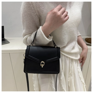 Detail view of black minimalist crossbody bag with gold double-ring lock on a model