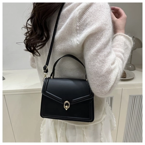 Détail du sac à main élégant en cuir noir mat avec fermoir anneau doré et bandoulière réglable