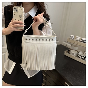 Gros plan du sac cabas blanc avec rivets métalliques, franges et texture grainée