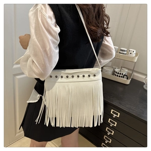 Gros plan sur un sac à franges blanc bohème avec clous en métal et cuir grainé