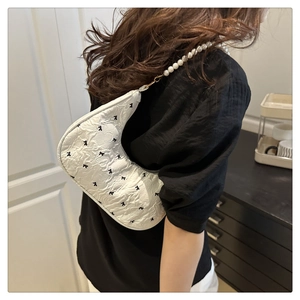 Détails du sac blanc en forme de croissant avec nœuds noirs et bandoulière en perles