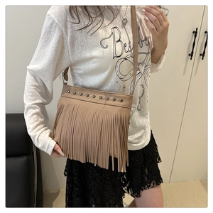 Détail du sac bandoulière de ton terre avec de longues franges et des rivets en métal
