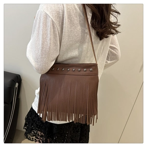 Détail du sac bandoulière marron en cuir synthétique avec rivets argentés et longues franges