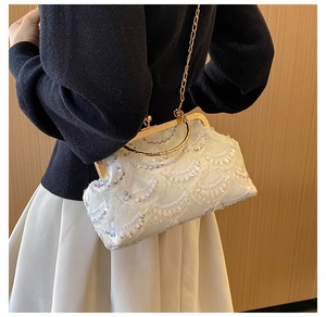 Detail of white sequin evening bag with gold metal handle and elegant chain strap