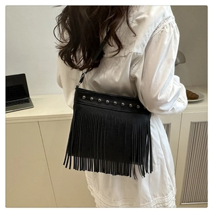 Primer plano del bolso tote negro con tachuelas plateadas y flecos largos modernos