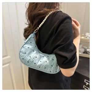 Détail du sac croissant bleu clair avec nœuds noirs et bandoulière en perles décorative