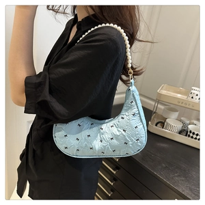 Détail du sac demi-lune matelassé bleu clair avec broderie nœud et bandoulière en perles