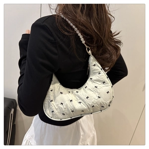 Détail du sac matelassé blanc avec motifs nœuds et bandoulière élégante en perles