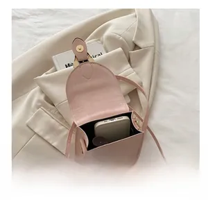 Détail de l'intérieur d'un sac à bandoulière rose contenant smartphone et rouge à lèvres
