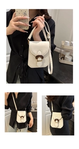 Detail of cream mini crossbody bag featuring a vintage wood-grain buckle and gold accents