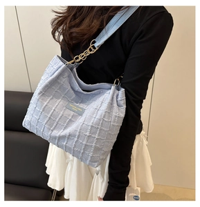 Detail of light blue checkered tweed tote with metallic chain strap and leather logo