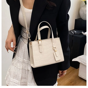 Close-up of elegant cream white handbag with crocodile embossing and golden metal hardware