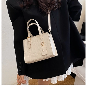 Close-up of cream crocodile pattern bag with gold hardware on a professional model