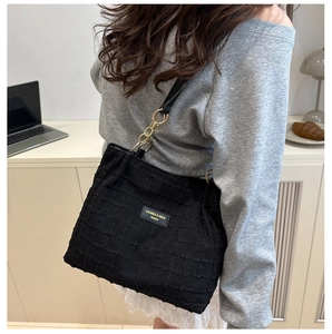 Detail of black checkered tote bag with gold chain and brand logo in a lifestyle setting