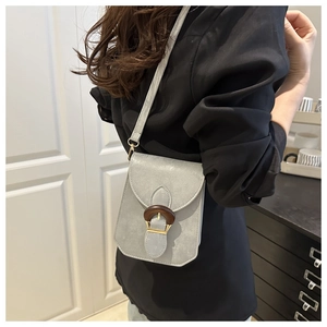 Vue détaillée du petit sac bandoulière gris clair avec boucle en bois et fini texturé