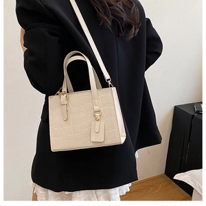 Detail of cream croc-embossed square bag with top handle and strap on model