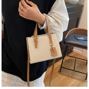Detail of off-white square crossbody bag with luxury crocodile texture and brown handle