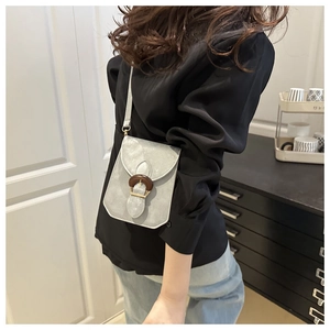 Vue détaillée du petit sac bandoulière gris avec une boucle ronde en bois élégante