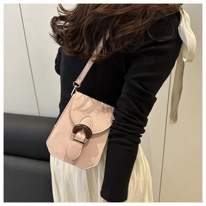Vue détaillée latérale du petit sac rose nude avec boucle en bois porté par le mannequin