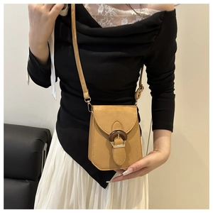 Détail d'un petit sac bandoulière camel avec boucle ronde décorative en grain de bois