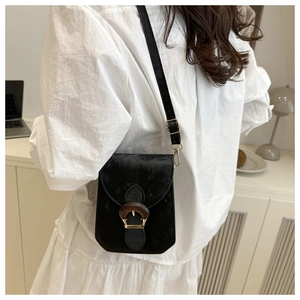 Détail d'un sac bandoulière en velours noir avec boucle dorée vintage sur une robe blanche