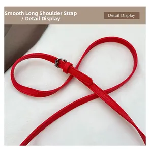 Détail de la bandoulière réglable en cuir rouge grainé avec boucle argentée
