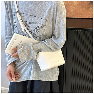 Gros plan du sac bandoulière blanc à texture de litchi et lettrage Fashion délicat