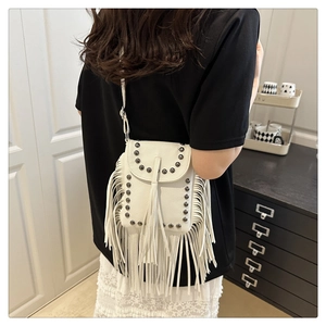 Detalle de bolso bandolera blanco con flecos y remaches sobre cuero sintético granulado