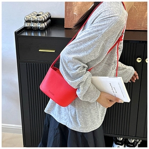 Détail d'un sac seau rouge à texture grainée avec inscription fashion estampillée