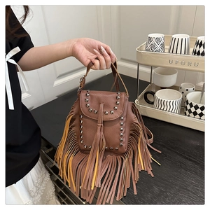 Detalle del bolso marrón con flecos, tachuelas plateadas y cuero texturizado