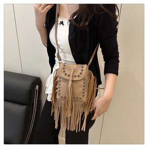 Detalle de bolso bandolera caqui con remaches plateados y flecos largos de cuero