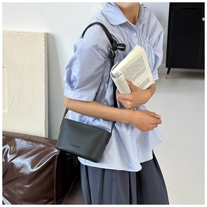 Détail d'un mini sac bandoulière noir avec texture grainée et logo Fashion embossé