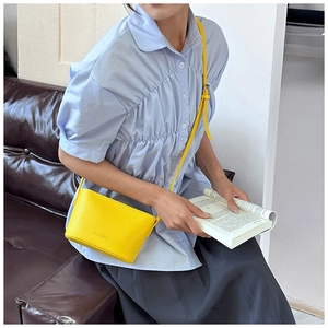 Détail d'un sac seau jaune vif avec texture lychee dans une scène de style de vie