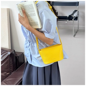 Détail d'un sac bandoulière en cuir jaune vif porté par un mannequin dans un cadre lifestyle