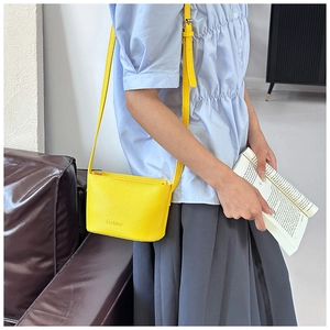 Détail du sac bandoulière jaune texture litchi avec gravure Fashion sur mannequin