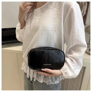 Détail du sac ovale noir avec bandoulière en chaîne argentée et lettrage mode