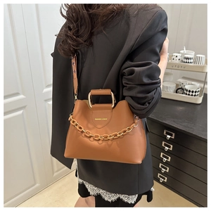 Detail of tan leather bucket bag with gold chain decoration and printed wide shoulder strap