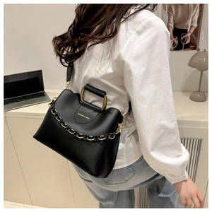 Detail of black leather bucket bag with U-shaped metal handle and gold chain decoration