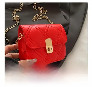 Macro shot of red quilted crossbody bag with gold chain strap and metallic twist lock